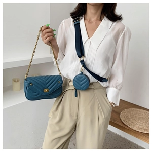 Detail of navy quilted crossbody bag with golden chain and round coin purse pendant