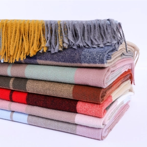 Detailed view of stacked colorful plaid scarves with soft fringe edges and fabric texture