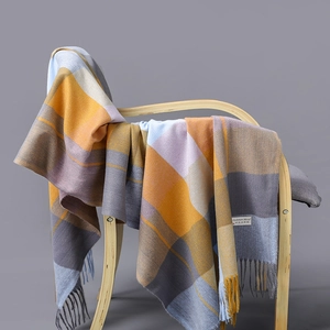 Plaid cashmere blend scarf in blue and yellow with fringes on a wooden chair