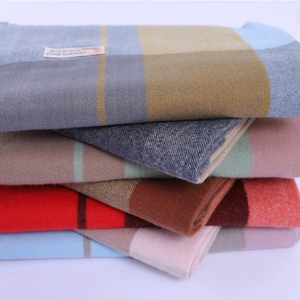 Close-up of stacked cashmere blend scarves showing various colorful plaid patterns and textures