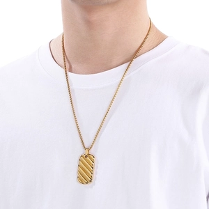 Close-up of a men's 18k gold-plated stainless steel bar pendant worn on a white T-shirt