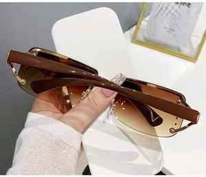 Detail of rimless y2k sunglasses with brown gradient lenses and gold metal hinges