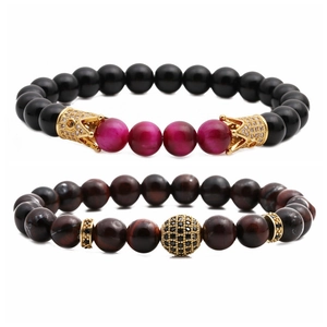 Dettaglio del set di braccialetti con pietre occhio di tigre e ciondoli a corona oro