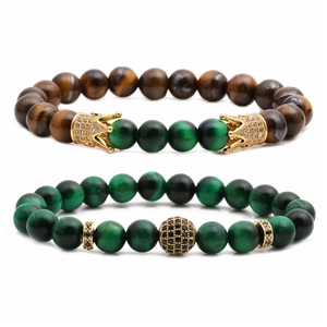 Dettaglio delle perle in occhio di tigre e corona dorata su un set di bracciali fatti a mano