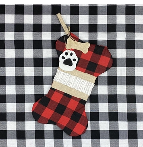 Détail de chaussette de Noël en forme d'os avec carreaux rouges et noirs et empreinte