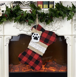 Détail d'une chaussette de Noël en forme d'os à carreaux rouges et noirs sur cheminée
