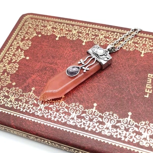 Detail view of hexagonal rose quartz pendant with silver sword pattern and purple stone