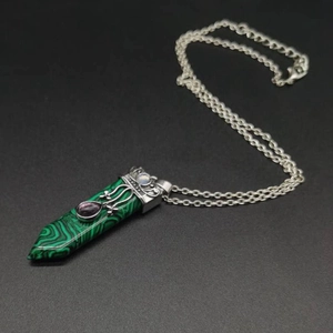 Detailed view of malachite pendant with silver engraving and purple amethyst stone