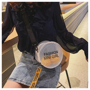 Detail view of round clear PVC shoulder bag with black strap and yellow decorative ribbon
