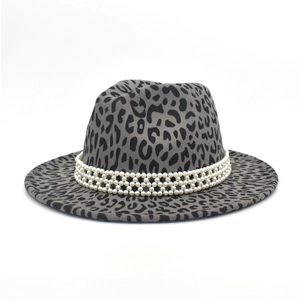 Détail du chapeau fedora léopard avec bande décorative à triple rangée de perles blanches