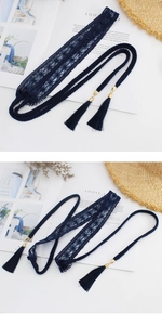 Detail of dark blue lace woven belt with elegant tassels and gold metal accents