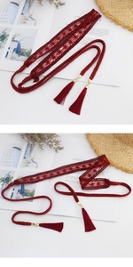 Close-up of wine red woven waist belt with fringe tassels and gold metallic hardware
