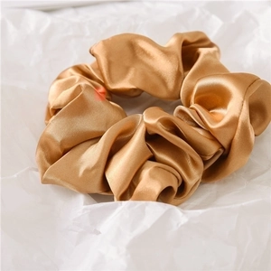 Detailed macro view of large champagne satin scrunchie with soft silk texture