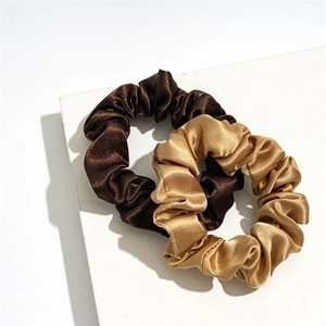 Set of two elegant satin scrunchies in dark brown and champagne gold on a white base