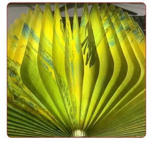 Detail of a foldable book lamp featuring traditional Chinese landscape art on paper pages