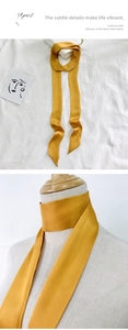 Golden yellow skinny silk scarf shown tied on a bag handle and worn around the neck