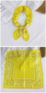 Detailed flat lay of a yellow silk-like paisley square scarf showing intricate pattern