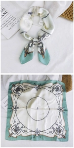 Close-up of mint green silk scarf with vintage chain patterns and satin luster detail