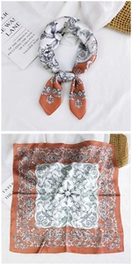 Detail of a bright orange silk square scarf with vintage baroque patterns and satin texture
