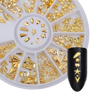 Close-up of golden metal nail charms in a white carousel box for DIY manicure design