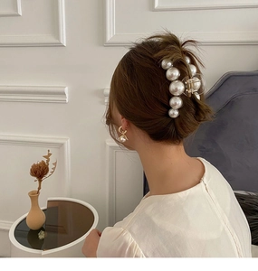 Close-up of elegant pearl hair claw clip and matching pearl earrings on a model