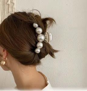 Detail shot of a large transparent hair claw clip with gradient white pearls on model