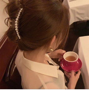 Close-up of elegant pearl hair claw clip securing a bun on model in a soft-lit setting