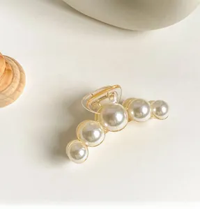 Detailed view of amber plastic hair claw clip with five gradient size white pearls