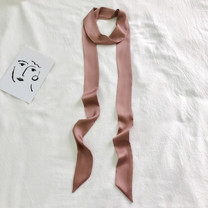 Pink narrow long silk scarf for handbag handles and hair decoration on white fabric