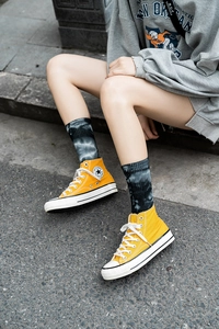 Close-up of yellow high-top canvas sneakers with stylish tie-dye socks on stone steps