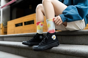 Street style shot of colorful tie-dye crew socks worn with high-top daisy sneakers