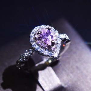 Macro shot of luxury silver ring featuring a pear-cut purple gemstone and diamond halo