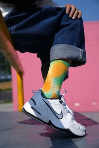 Close-up of yellow, orange and green tie-dye socks paired with white sneakers outdoors