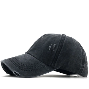 Detail view of washed cotton baseball cap featuring vintage distressed holes and side embroidery
