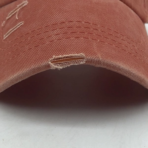 Detail of distressed brim and stitched edge on washed cotton ponytail baseball cap
