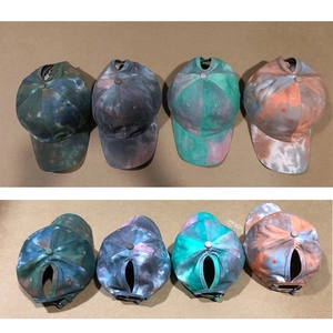 Detailed macro view showing four colorful tie-dye ponytail baseball caps in a row.