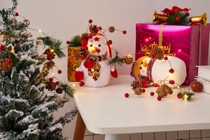 Close-up of plush Christmas snowman figures with pine cones and LED copper wire lights