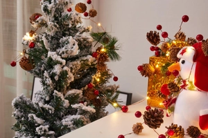 Close-up of LED Christmas string lights with pine cones, red berries and a small snowman