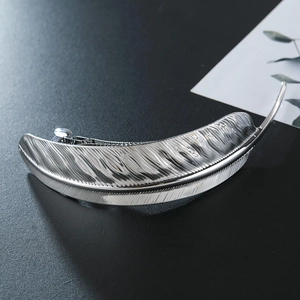 Elegant silver feather hair clip with metallic finish and intricate texture on black surface