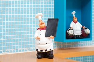 Close-up of a vintage chef figurine holding a chalkboard sign for cafe and kitchen decor