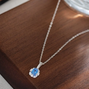 Exquisite S925 silver necklace featuring a blue oval zircon pendant on a wooden surface