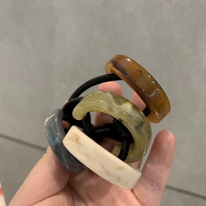Detail view of four marble-patterned acetate hair ties in various elegant colors