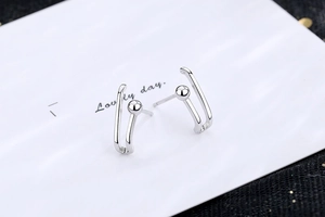 Macro shot of silver paperclip-style stud earrings with U-shape design and metal beads