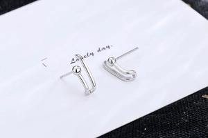 Detail of silver paperclip earrings with U-shape design and beads on white card