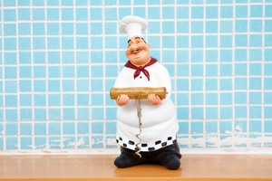 Detail of vintage chef figurine bottle opener with metal screw and wooden handle on counter