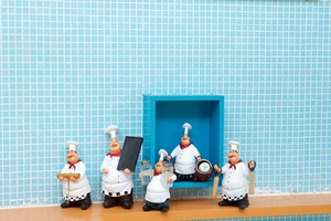 Set of five vintage chef resin figurines holding kitchen tools on a rustic shelf