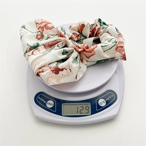Floral print oversized scrunchie with long ribbons on a white scale showing 12.9g weight