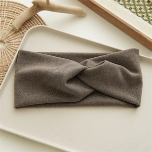 Detail of brown knitted headband with a knot design on a minimalist beige tray