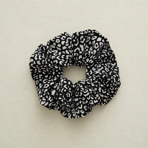 Close-up of fabric hair scrunchie featuring a classic black and white leopard print pattern