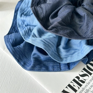 Denim fabric oversized scrunchies in dark, medium, and light blue washes on a magazine